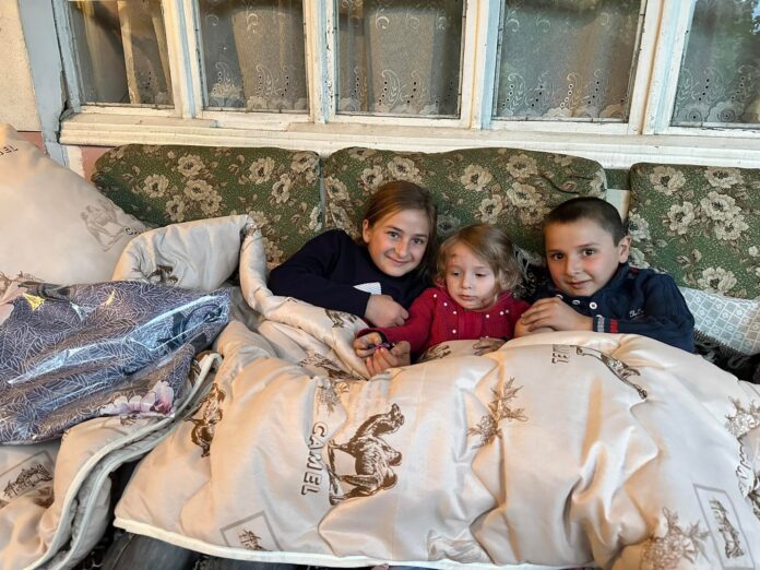 Refugee children from Artsakh cuddling up under warm blankets on new beds in Tavush Province