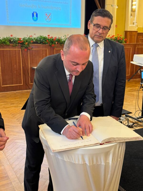 Ambassador Viktor Yengibaryan signing the Golden Book of Naumburg, with Mayor Armin Müller of Naumburg behind him watching